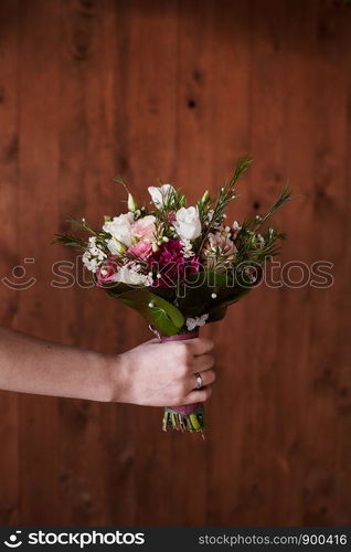 Stylish wedding bouquet bride of pink roses, white carnation and green flowers and greens with ribbons lying. Close up. Side view. Wedding decor. Artwork. beautiful wedding bouquet. beautiful wedding bouquet. Stylish wedding bouquet bride of pink roses, white carnation and green flowers. Side view. Wedding decor.