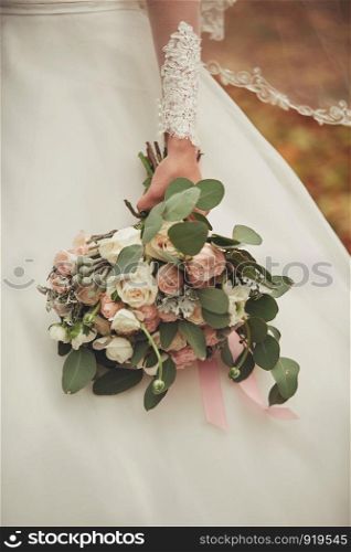 Stylish wedding bouquet bride of pink roses, white carnation and green flowers and greens with ribbons lying. Close up. Side view. Wedding decor. Artwork. beautiful wedding bouquet. beautiful wedding bouquet. Stylish wedding bouquet bride of pink roses, white carnation and green flowers. Side view. Wedding decor.
