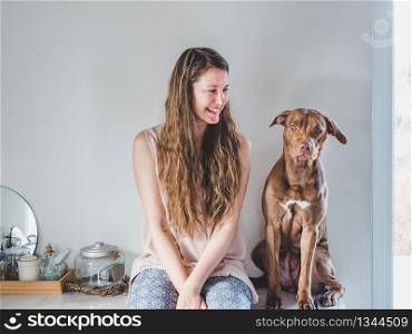 Stylish woman and a charming puppy. Close-up, indoors. Studio photo, white color. Concept of care, education, obedience training and raising pets. Stylish woman and a charming puppy. Close-up