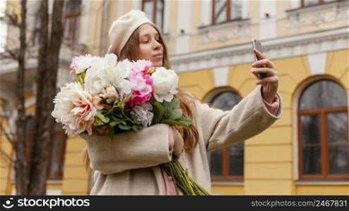stylish woman holding bouquet flowers outdoors spring taking selfie