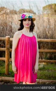 Stylish woman with a red dress and straw hat with flowers in the field