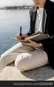 stylish woman writing notebook outdoors
