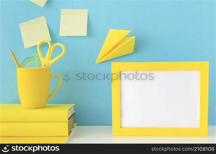 stylish workplace with yellow frame paper plane