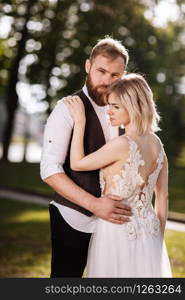 stylish young beautiful couple hugging in spring park on a sunny day. wedding portrait. Woman in white dress. stylish young beautiful couple hugging in spring park on a sunny day. wedding portrait. Woman in white dress.