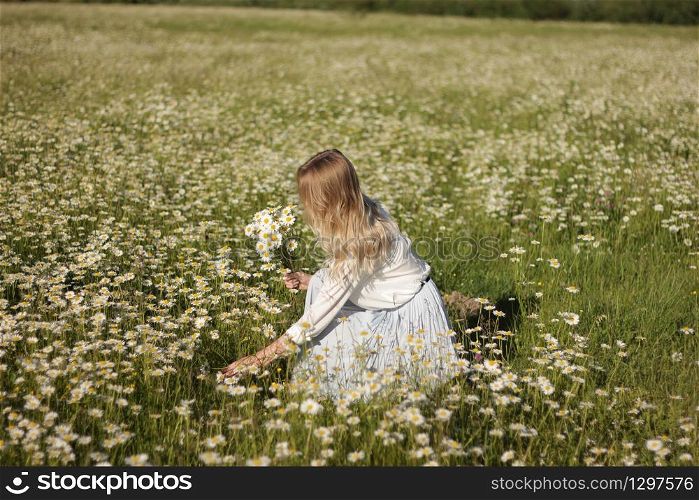stylish young blonde woman in a field with daisies on a sunny summer day. pretty girl relaxing outdoor, having fun, holding plant, happy young lady and spring green nature, harmony concept.. stylish young blonde woman in a field with daisies on a sunny summer day. pretty girl relaxing outdoor, having fun, holding plant, happy young lady and spring green nature, harmony concept
