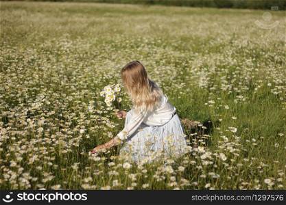stylish young blonde woman in a field with daisies on a sunny summer day. pretty girl relaxing outdoor, having fun, holding plant, happy young lady and spring green nature, harmony concept.. stylish young blonde woman in a field with daisies on a sunny summer day. pretty girl relaxing outdoor, having fun, holding plant, happy young lady and spring green nature, harmony concept