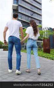 Stylish young couple is spending time together outdoors. Attractive woman and handsome man are posing in the street