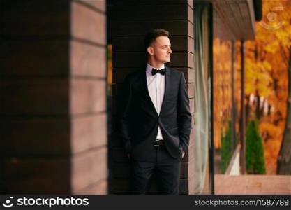 stylish young groom in a black suit in the autumn park on wedding day.. stylish young groom in a black suit in the autumn park on wedding day