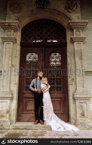 stylish young man with beard and woman in luxury long dress on wedding day near the castle. Romantic love in vintage atmosphere street. stylish young man with beard and woman in luxury long dress on wedding day near the castle. Romantic love in vintage atmosphere street.