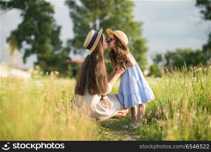 Stylish young mother with toddler girl walking on nature