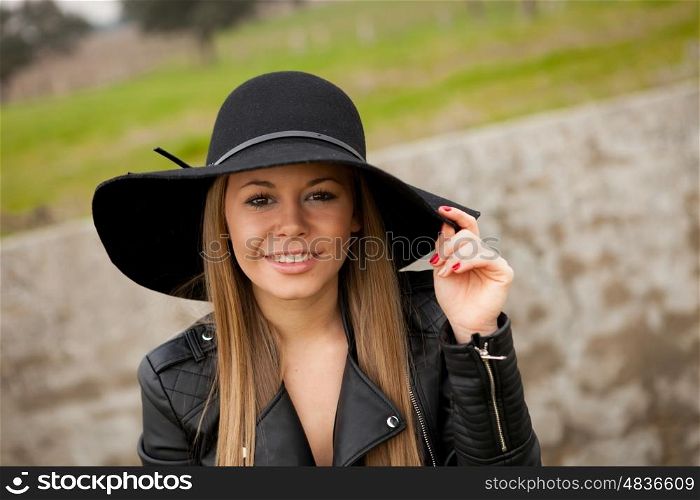 Stylish young woman with beautiful hat in the field