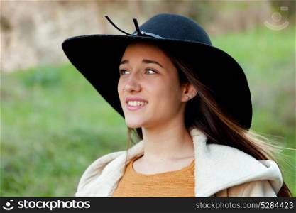 Stylish young woman with big hat in the field