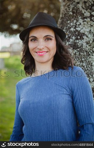 Stylish young woman with black hat in the field