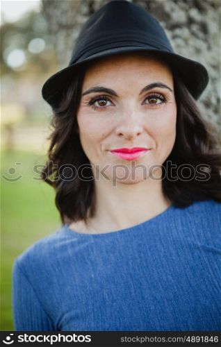 Stylish young woman with black hat in the field