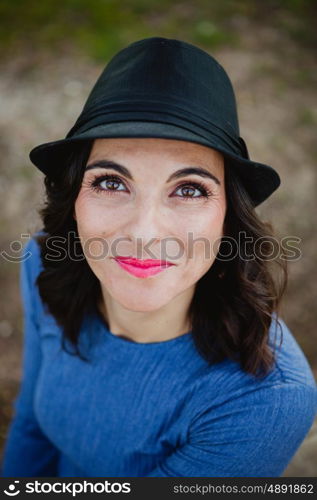 Stylish young woman with black hat in the field