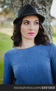 Stylish young woman with black hat in the field