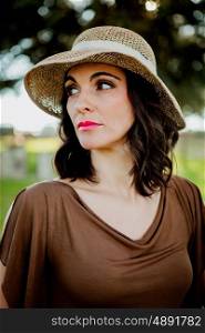 Stylish young woman with straw hat in the field