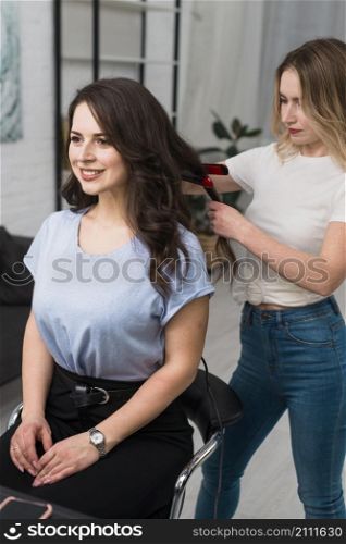 stylist curling hair young woman