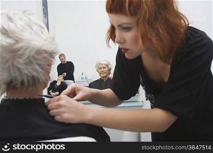 Stylist makes finishing touches to elderly woman&acute;s hair