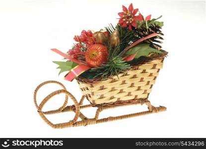 stylized wicker christmas straw sleigh with strobiles, gold, red present and balls, fir-tree&rsquo;s leafs isolated on white