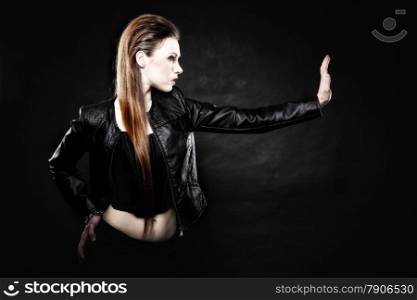 Subculture beauty punk girl in leather jacket making stop gesture black background