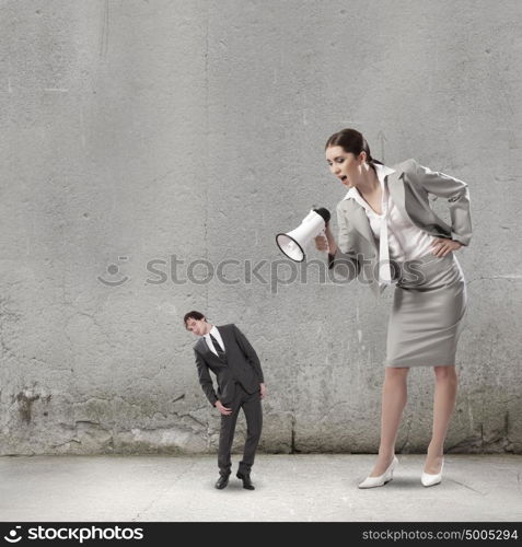 Subordination concept. Businesswoman screaming in megaphone on man colleague