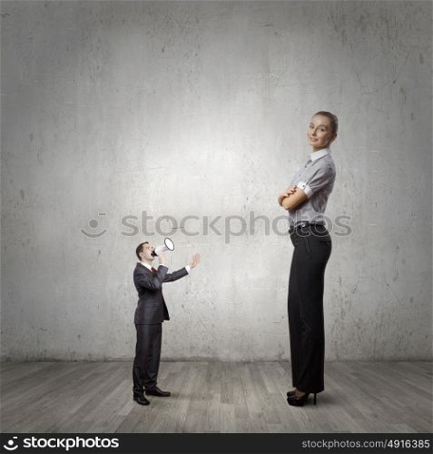 Subordination concept. Small businessman screaming in megaphone on woman colleague