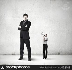 Subordination concept. Small businesswoman screaming in megaphone on colleague of huge size
