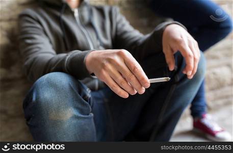 substance abuse, addiction, people and bad habits concept - close up of young man smoking cigarette outdoors