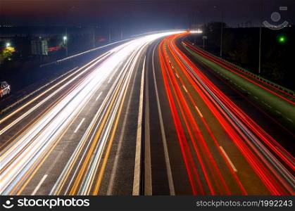 Suburban highway at night. Traces from headlights and taillights of heavy traffic. Night Car Traffic With Trails on a Suburban Highway