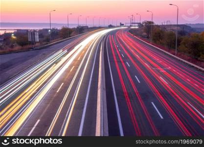 Suburban highway in the evening after sunset. Traces from headlights and taillights of heavy traffic. Sunset Car Traffic With Trails on a Suburban Highway