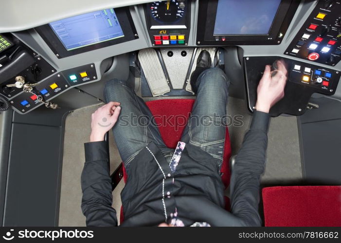 Subway driver in the cockpit, behind the control panel, seen from above