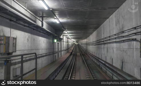 Subway rails in tunnel with wires on cement walls . Subway rails in tunnel
