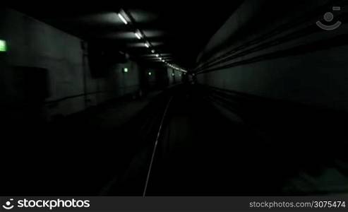 Subway train moving in the dark tunnel and arriving at the station. Paris, France