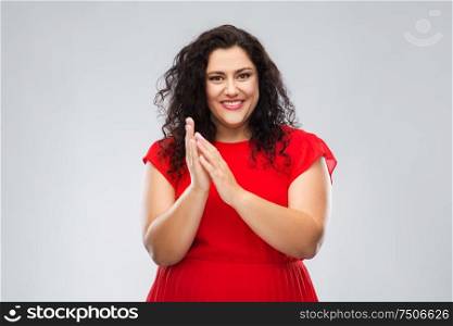 success, acknowledgment and appreciation concept - portrait of happy woman in red dress applauding over grey background. happy woman in red dress applauding