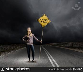 Success ahead. Young woman satnding on road with signboard