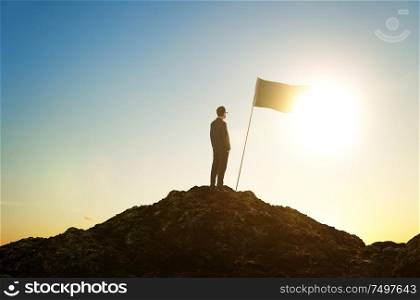 Success and achievement concept , silhouette of businessman with flag on mountain top .