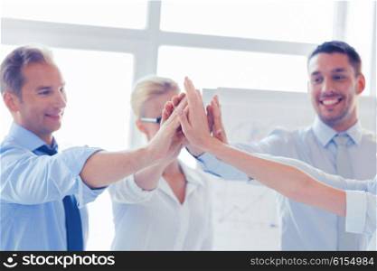 success and winning concept - happy business team giving high five in office. happy business team giving high five in office