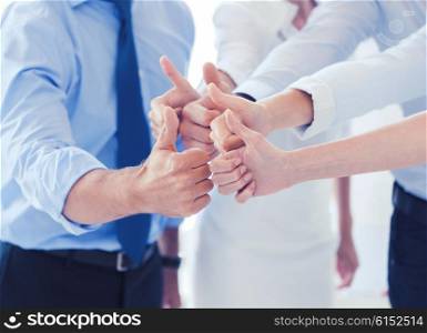 success and winning concept - happy business team showing thumbs up in office. business team showing thumbs up in office