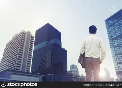Success business and finance concept. Businessman looking to hight modern business building center city at sunrise. Picture for add text message. Backdrop for design art work.