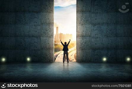 Success businessman cheering against concrete wall with huge door ,sunrise scene city skyline outdoor view .