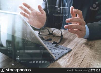 success businessman hand using eyeglass,digital tablet docking smart keyboard on wood desk,icons graphic screen effect