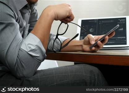 success businessman hand using eyeglass,smart phone,digital tablet docking smart keyboard on wood desk