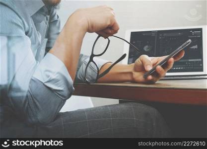 success businessman hand using eyeglass,smart phone,digital tablet docking smart keyboard on wood desk