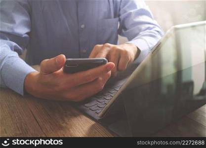 success businessman hand using smart phone,digital tablet docking smart keyboard,on wooden desk,filter effect