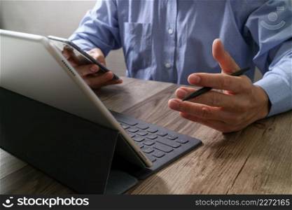success businessman hand using stylus pen,digital tablet docking smart keyboard on wooden desk