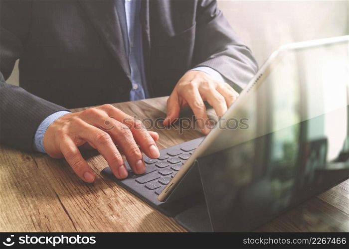 success businessman hand working with digital tablet docking smart keyboard on wooden desk,filter effect