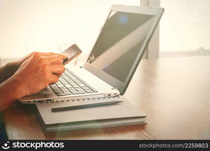 success businessman using smart phone with laptop computer on wooden desk
