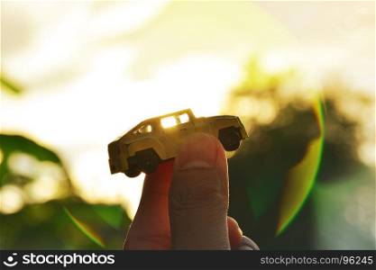Success concept, Holding toy car in the sky at sunset. Dream car