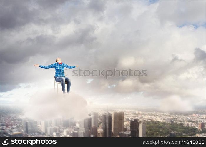 Success concept. Young girl sitting in chair high in sky